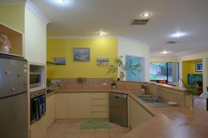 una grande cucina con pareti gialle e lavandino di Airport 6BR Haven - Quiet Yard & AC a Perth