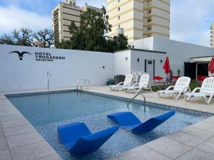 内科切阿Hotel Trocadero的一座带蓝色躺椅的游泳池,位于大楼旁