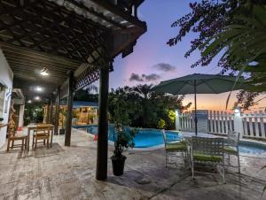 a patio with a table and chairs and an umbrella at Hotel Capitan Playa Tela in Tela