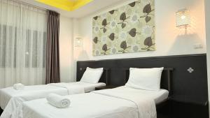 バンコクにあるIssara House Bangkokの白いシーツが敷かれたホテルの部屋にベッドが2つある