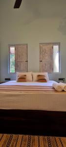 uma cama grande em um quarto com duas janelas em Amanda Mirissa em Mirissa