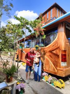 un grupo de personas de pie delante de una furgoneta en Bus Resort, en Amphoe Phrao