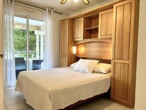 une chambre avec un lit avec une tête de lit en bois dans l'établissement Appartement climatisé 2 pièces avec terrasse et parking au Lavandou - FR-1-251-854, au Lavandou