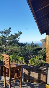 a wooden table and chair on a patio with a view of the ocean at Amazing Getaway Oceanview with treehouse feel in Manchester +24 photos