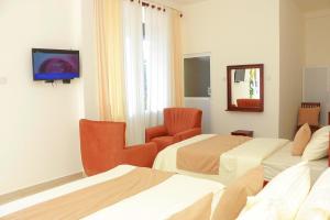 una camera d'albergo con due letti e una tv di Hotel Helani Pvt Ltd a Midigama East Altre 78 foto