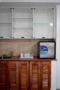 a kitchen with wooden cabinets and a microwave at El Pergentina Holiday Beach Resort in Siquijor