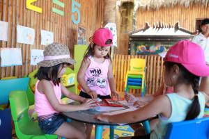 three girls wearing pink hats sitting at a table at Novotel Lombok Resort & Villas in Kuta Lombok