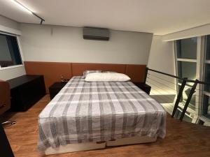 a bedroom with a bed with a plaid blanket at Loft Duplex com Hidromassagem in Florianópolis