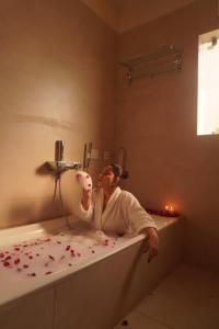 a woman sitting in a bathtub with flowers on it at The Lavish Stay in Varanasi