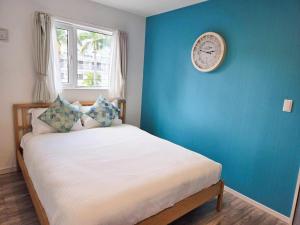 a bedroom with a bed with a clock on the wall at ビーチから徒歩6分広々としたテラスBBQ露天ジャグジーMorley2 in Onna +39 photos
