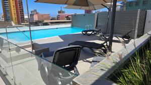 a swimming pool with two chairs and an umbrella at Home life 28 in Iquique