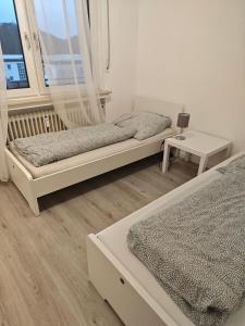 a bedroom with two beds and a table and a window at Work and Stay Plettenberg 90 Qm 7 Betten 3 Schlafzimmer mit Balkon und Kraftraum 44 oben in Plettenberg