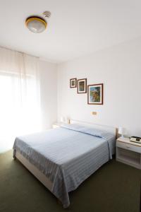 a white bedroom with a bed and a window at Hotel Krizman in Monrupino