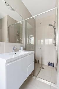 a white bathroom with a sink and a shower at Peaceful Stay at Ettalong Beach in Ettalong Beach