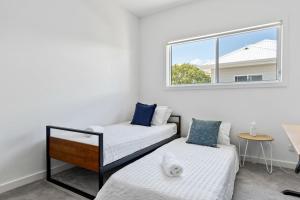 a white room with two beds and a window at Peaceful Stay at Ettalong Beach in Ettalong Beach
