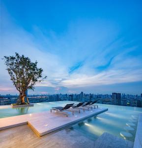 a pool with lounge chairs on the roof of a building at Modern condo nr BTS ONNUT WIFI with workroom in Bangkok