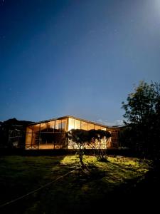 a large glass building with a tree in front of it at Chiloe Loft & Glamp in Chonchi