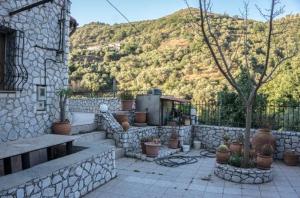 a stone patio with potted plants in front of a mountain at Diving into silence - Traditional Stone House in Kakópetros +26 photos