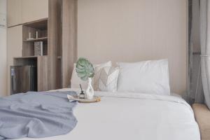 ein weißes Bett mit einer Pflanze in einer Vase darauf in der Unterkunft Best Choice and Cozy Studio Sky House BSD Apartment By Travelio in Tangerang + 16 Fotos