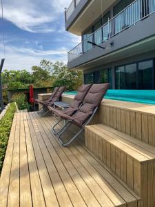 a pair of chairs sitting on a deck next to a swimming pool at Seaview Eagles Nest Apartment 3 in Nai Harn Beach
