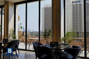 a restaurant with tables and chairs and large windows at Andalus Hotel in Baghdād