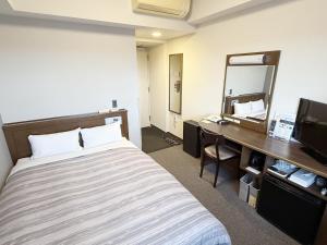 a hotel room with a bed and a desk and a mirror at Hotel Route-Inn Ichinoseki Inter in Ichinoseki +28 photos