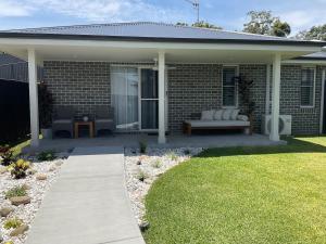 a patio with a couch and a bench on a house at Chay's Guest House in Coffs Harbour