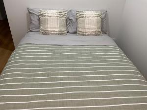 a bed with a gray and white striped sheets and pillows at Chay's Guest House in Coffs Harbour +3 photos