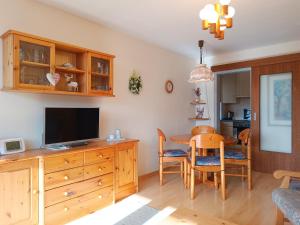 a living room with a television and a table with chairs at 2-Raum FeWo Gipfelglück - Hallenbad & Sauna in Fischen