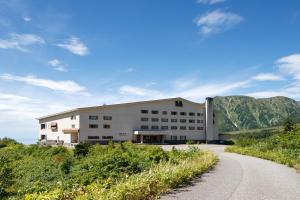 a building on a hill with a road in front at Midagahara Hotel in Tateyama