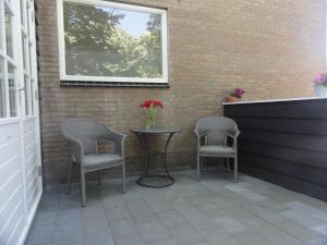 d'une terrasse avec 2 chaises, une table et une fenêtre. dans l'établissement Appartement Schuitvlot, à Domburg