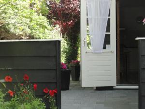 Appartement Schuitvlot في دومبورغ: باب أبيض على منزل به زهور حمراء