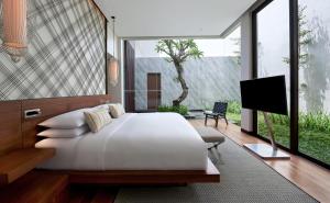 a bedroom with a large white bed and a flat screen tv at Renaissance Bali Uluwatu Resort & Spa in Uluwatu