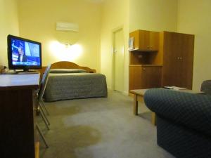 a hotel room with a bed and a television at Glenelg Motel in Adelaide