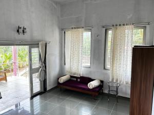 a living room with a purple couch in front of windows at Aanandee Villa in Pune