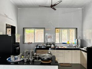 a kitchen with a black refrigerator and white cabinets at Aanandee Villa in Pune