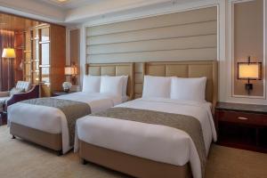 a hotel room with two beds and a chair at The Ritz-Carlton, Chengdu in Chengdu