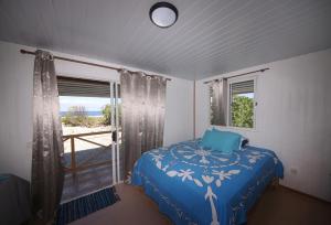 a bedroom with a blue bed and a window at Oteaeva Lodge - FAKARAVA in Rotoava