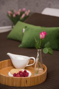 a tray with a vase with a rose and a plate of raspberries at MOKO Apartments in Krakow