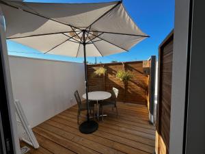 a table and chairs on a deck with an umbrella at Sun Oasis Les Tamaris in Bretignolles-sur-Mer