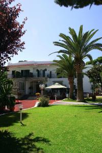 un bâtiment avec deux palmiers en face d'une cour dans l'établissement Hotel Lord Byron, à Ischia
