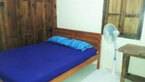 a bed with a blue pillow and a fan at Griya Harja Homestay in Borobudur