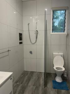 a white bathroom with a shower and a toilet at Drydens Creek Retreat in Ngatangiia