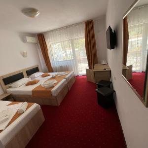 a hotel room with two beds and a television at Pensiunea Karina in Caciulata