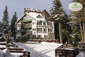 a large white building in the snow with trees at Vila Evergreen in Predeal