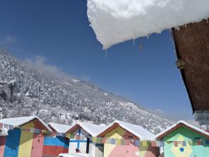 a row of houses covered in snow in front of a mountain at Soma Caves in Kulu +11 photos