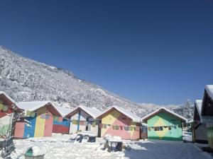 a row of colorful houses in the snow at Soma Caves in Kulu
