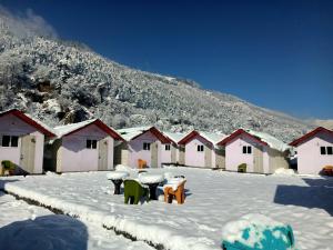 a group of houses in the snow with tables and chairs at Soma Caves in Kulu