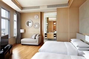 a bedroom with two beds and a couch and a mirror at Bangkok Marriott Hotel Sukhumvit in Bangkok