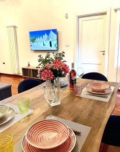 a wooden table with plates and flowers on it at Iaru-Bed Experience House in Alberobello